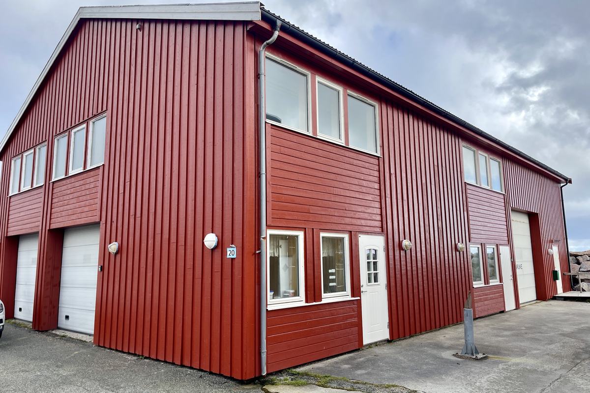 Det røde bygget i Siholmen på Sistranda der tannklinikken holder til, sett fra parkeringsplassen